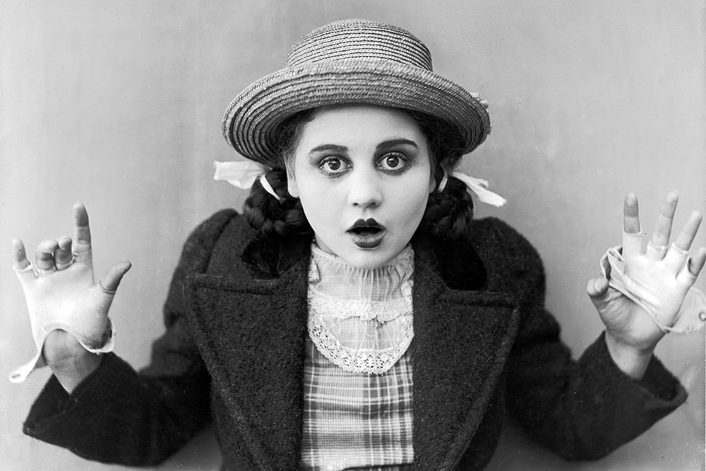 circa 1915:  American actor Bebe Daniels holds up her hands and opens her mouth in surprise, in a still from an unidentified silent film. She wears a straw hat and fingerless gloves with her hair in pigtails.  (Photo by American Stock/Getty Images)